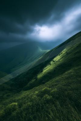A moody landscape of valley, mountains, field.