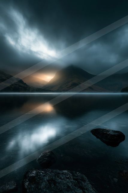 A serene lake reflects a glowing mountain peak under a moody sky with clouds, creating a tranquil yet dramatic atmosphere.