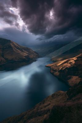 A black-toned moody photograph of valley, lakeside, dam.