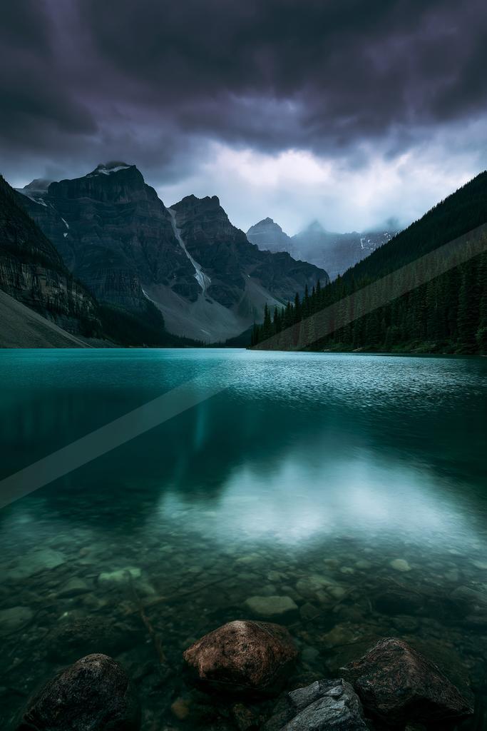 A green-toned moody photograph of lakeside, valley, canoe.