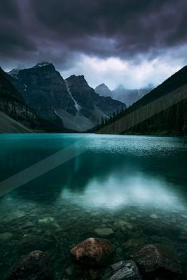 A green-toned moody photograph of lakeside, valley, canoe.
