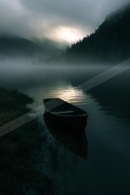 A black-toned moody photograph of canoe, lakeside, boathouse.