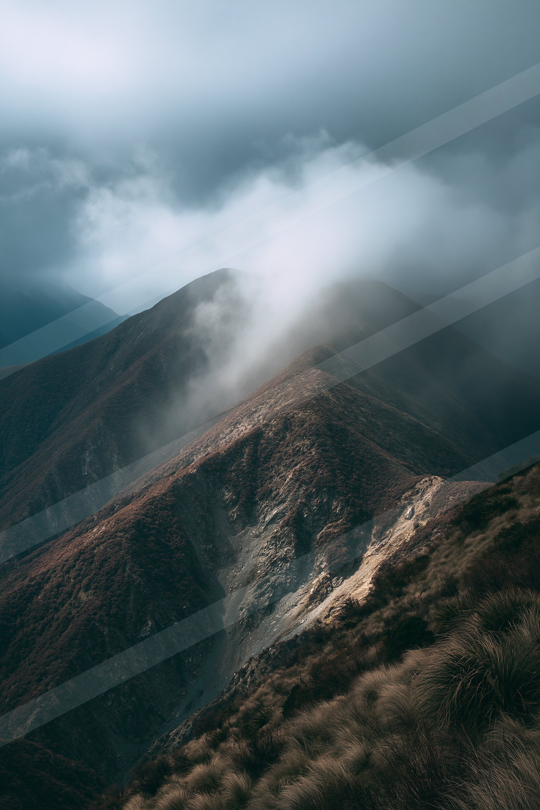 A rugged mountain range shrouded in mist and clouds, creating a mysterious atmosphere.