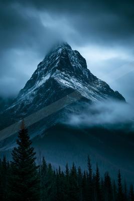 A dramatic landscape of mountains, fog.