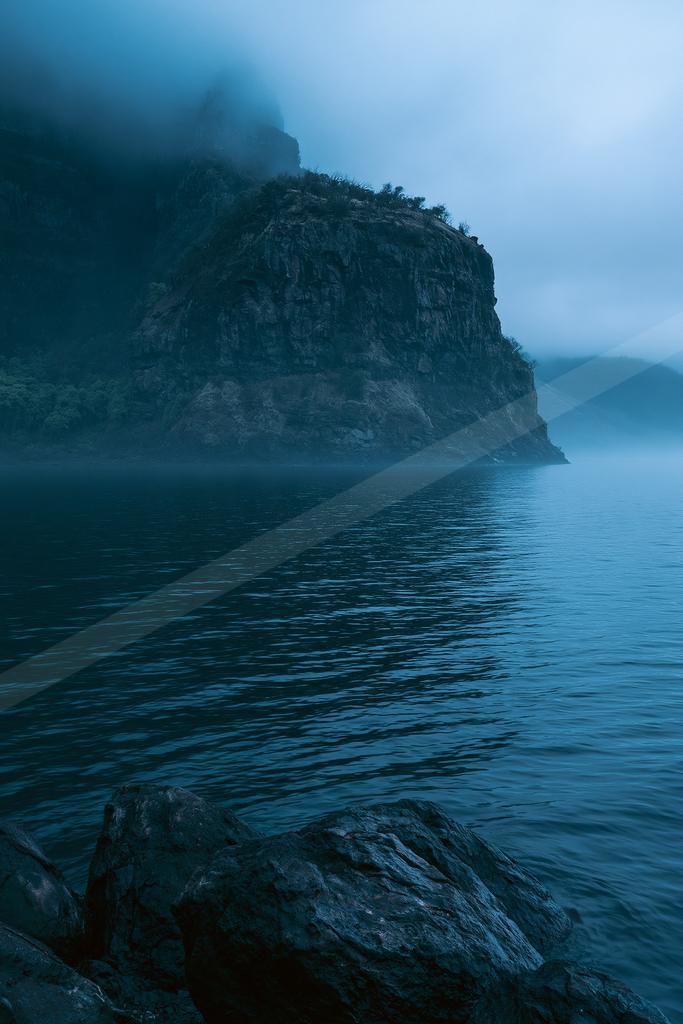 A blue hour long exposure water scene of ocean, lake, mountains.