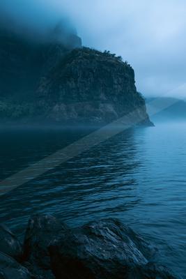 A blue hour long exposure water scene of ocean, lake, mountains.