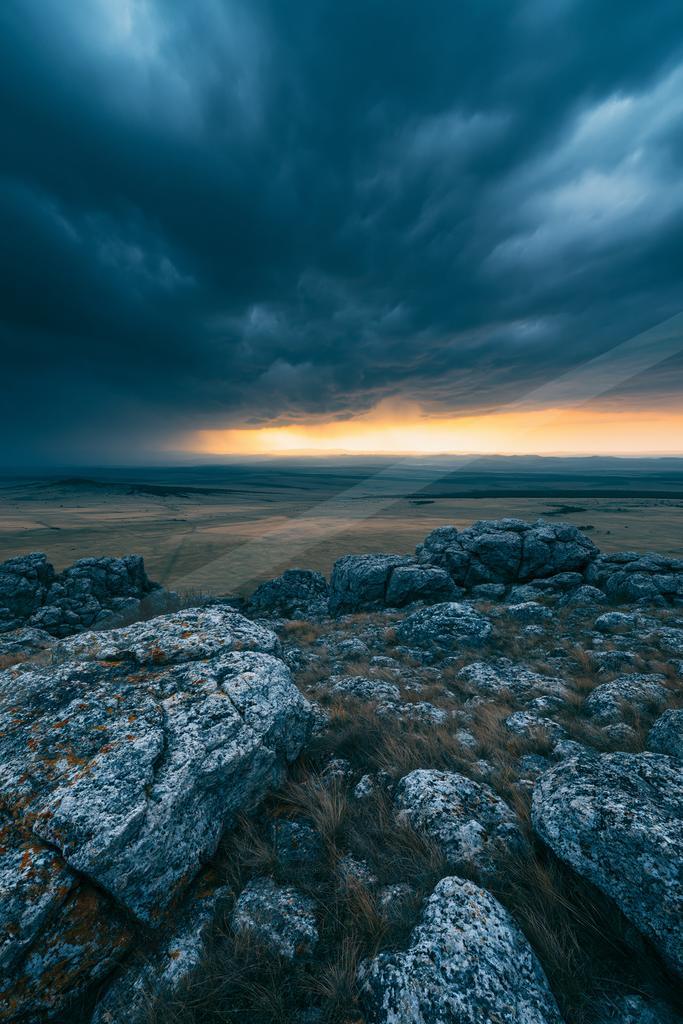A blue hour long exposure sky scene of storm, clouds, rocks.