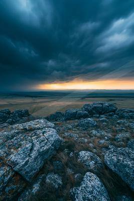 A blue hour long exposure sky scene of storm, clouds, rocks.