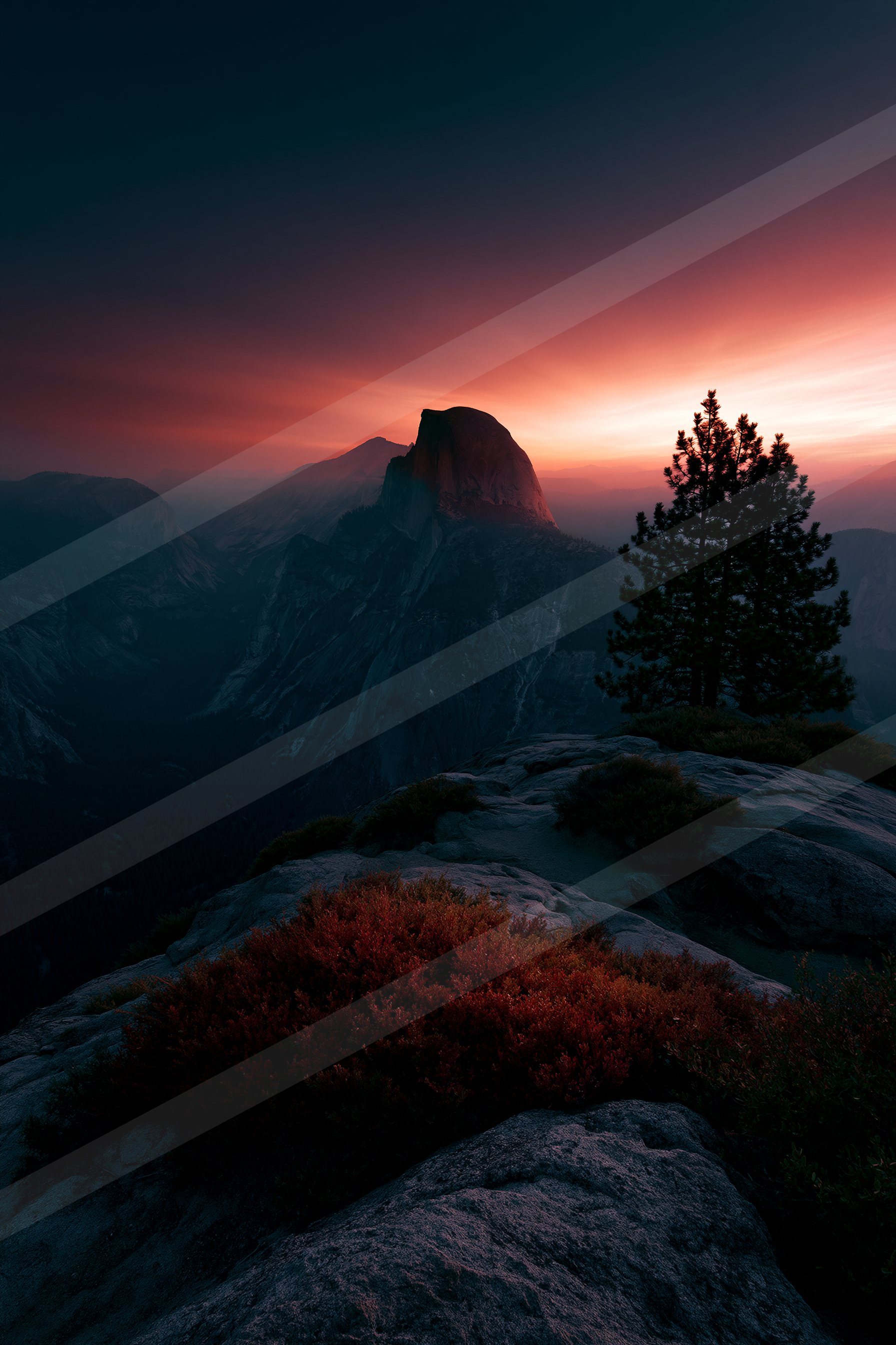 A breathtaking sunset scene featuring silhouetted trees and rugged mountains under a vibrant sky.