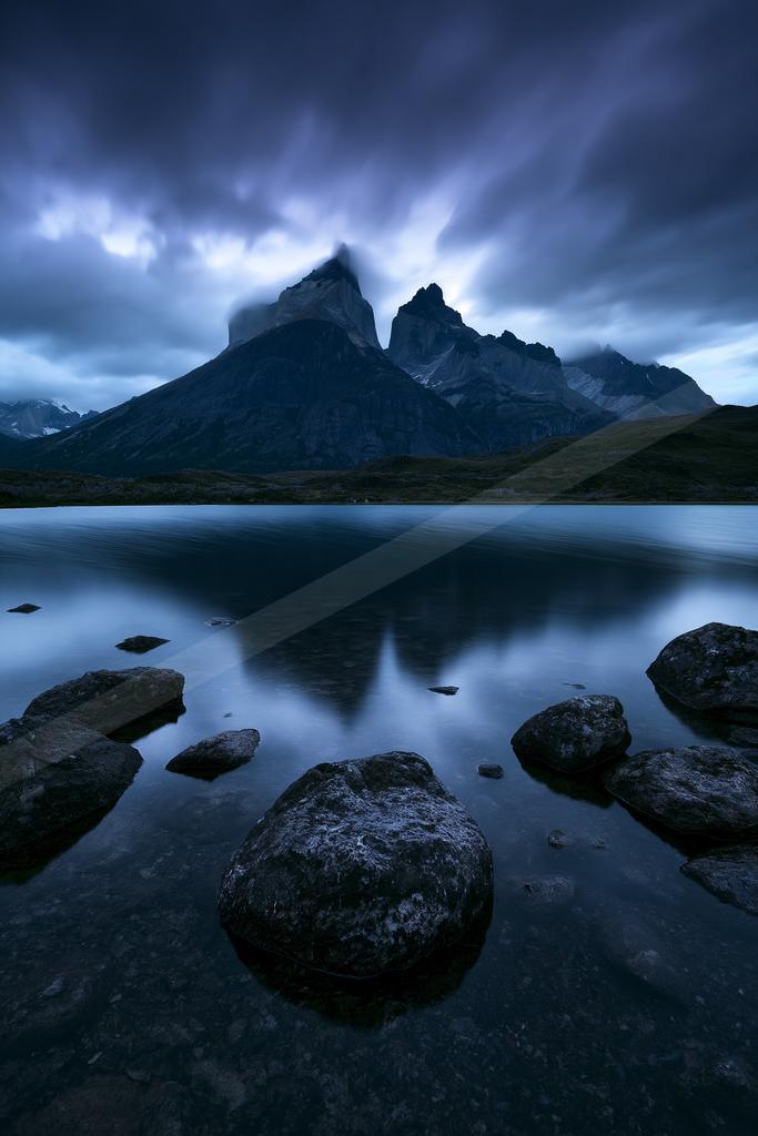 A blue hour long exposure water scene of lake, mountains, reflection.