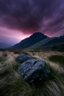 A moody landscape of mountains, field, valley.