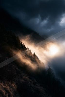 A mysterious high contrast sky scene of a sunbeams, fog.