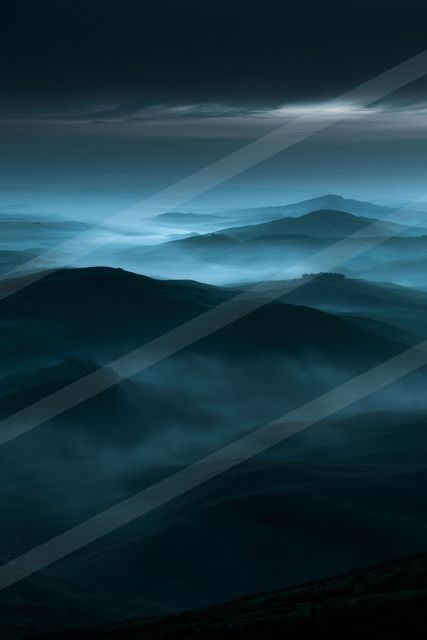 A serene mountain landscape shrouded in mist during twilight.