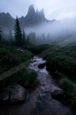 A black-toned moody photograph of valley, mountain tent, lakeside.