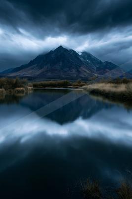 A blue hour long exposure water scene of lake, mountains, reflection.