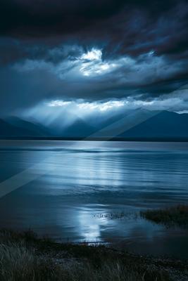 A blue hour long exposure water scene of lake, storm, clouds.