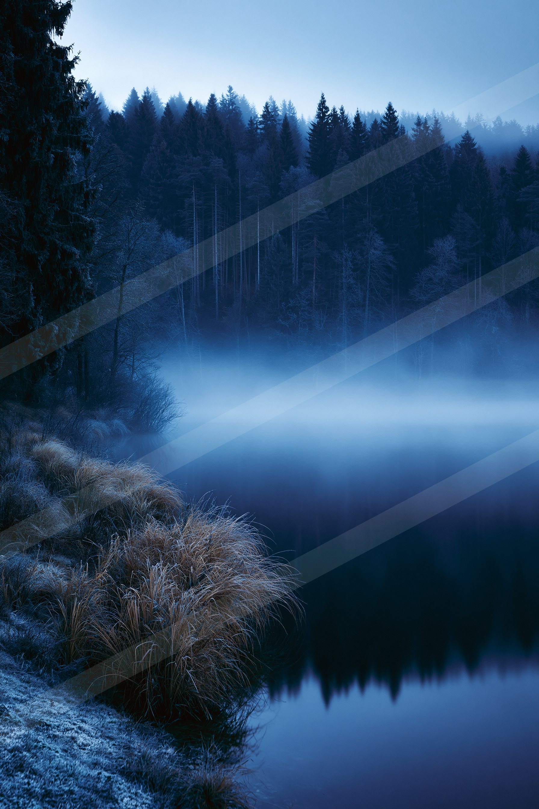 A blue hour high contrast water scene of a lake, fog.