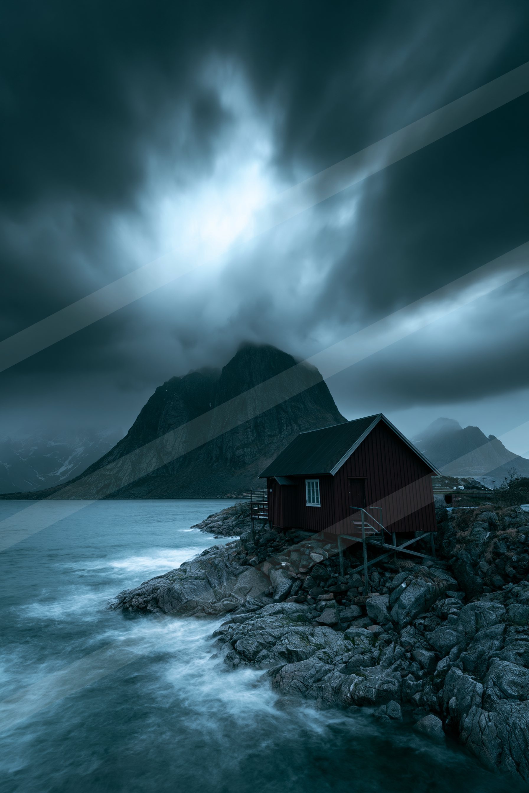 A small red cabin perched on rocky terrain near a turbulent sea, framed by dark storm clouds and towering mountains.