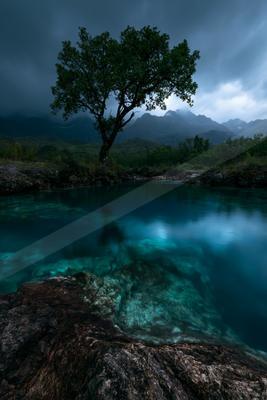 A blue hour long exposure water scene of lake, river, trees.