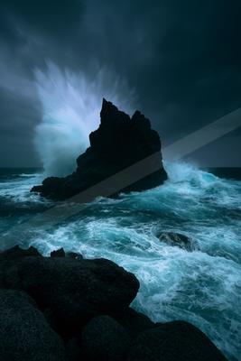 A blue hour water scene of ocean, waterfall, storm.