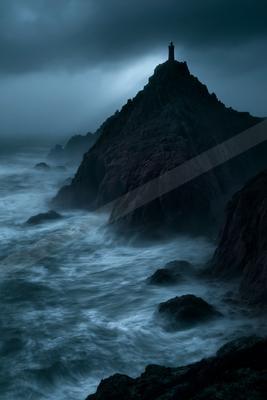 A solitary lighthouse stands atop a jagged rocky peak surrounded by turbulent ocean waves under a dark, stormy sky.