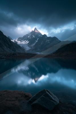 A blue hour long exposure water scene of lake, mountains, reflection.