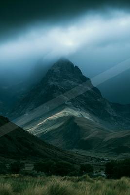 A moody high-key landscape of a volcano, fog.