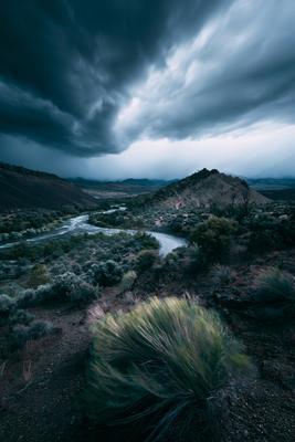 A green-toned moody photograph of valley, volcano, alp.