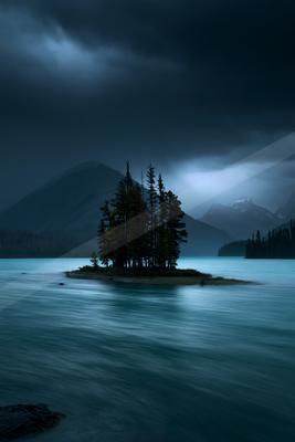 A blue hour water scene of lake, storm, mountains.