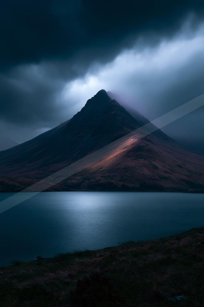 A dramatic long exposure landscape of mountains, lake.