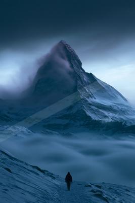 A dramatic landscape of mountains, storm, fog.