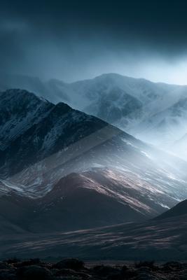 A dramatic landscape of mountains, fog.