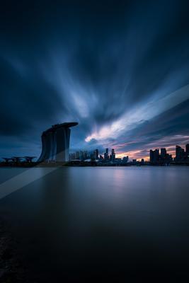 A black-toned moody photograph of pier, breakwater, fountain.