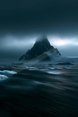 A dramatic water scene of ocean, mountains, fog.