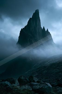A dramatic landscape of mountains, fog.