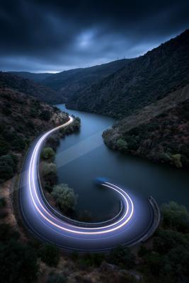 A moody landscape of valley, bridge, river.