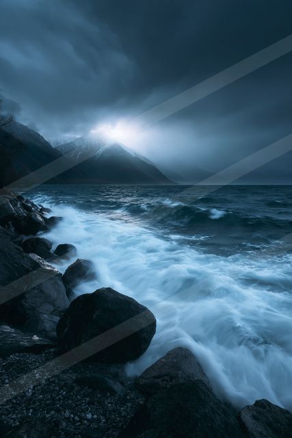 A powerful storm brews over a dark ocean as waves crash against rocky shores, illuminated by distant lightning or moonlight.
