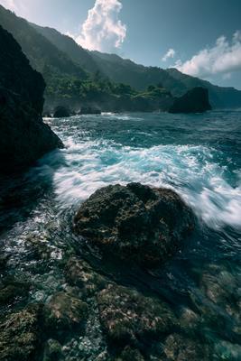 A serene water scene of ocean, beach, rocks.