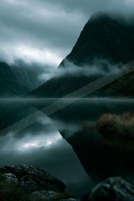 A night long exposure landscape of mountains, lake, fog.
