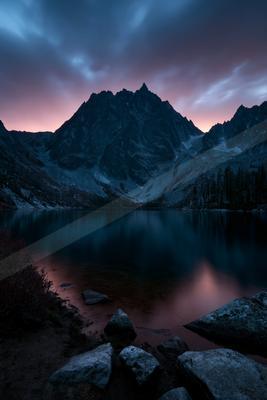 A blue hour long exposure water scene of lake, mountains, reflection.