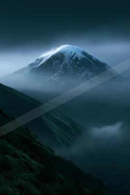 A dramatic landscape of mountains, fog.