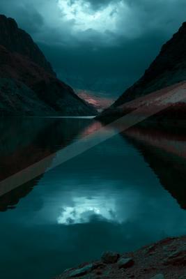 A serene canyon lake reflects the dramatic sky and rugged cliffs during twilight.