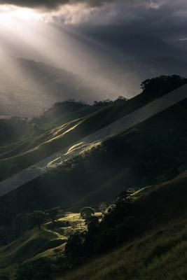 A black-and-white dramatic landscape of valley, mountains, storm.