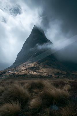 A black-toned bright photograph of volcano, cliff, mountain tent.