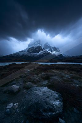 A brown-toned moody photograph of volcano, megalith, mountain tent.