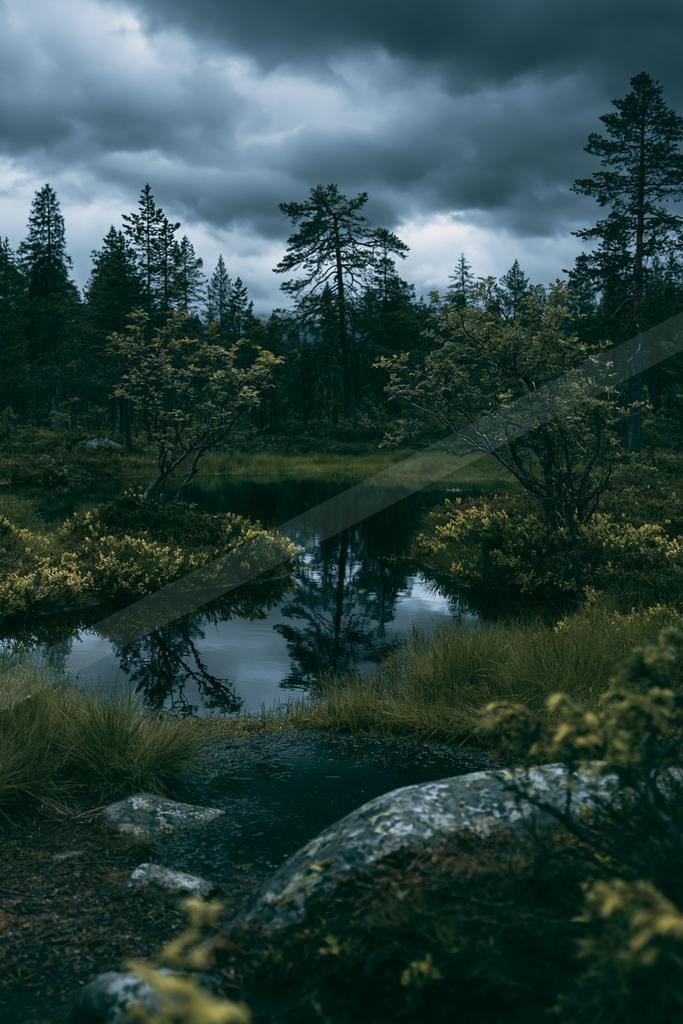 A black-toned moody photograph of valley, mountain tent, lakeside.