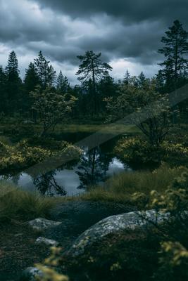 A black-toned moody photograph of valley, mountain tent, lakeside.