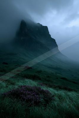 A moody landscape of mountains, field, valley.
