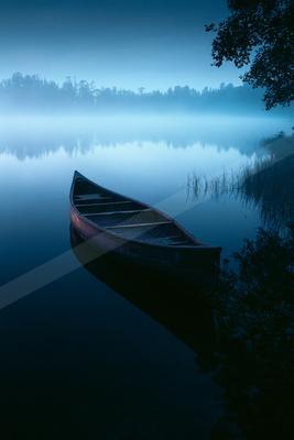 A black-toned moody photograph of canoe, paddle, lakeside.
