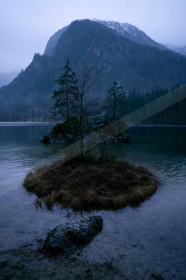 A serene water scene of lake, mountains, trees.
